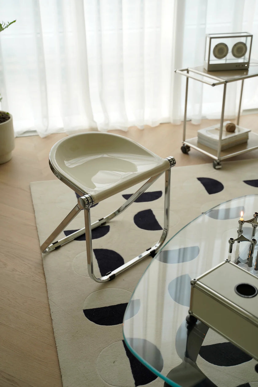 Modern room with a glass table, white folding chair, and decorative elements.