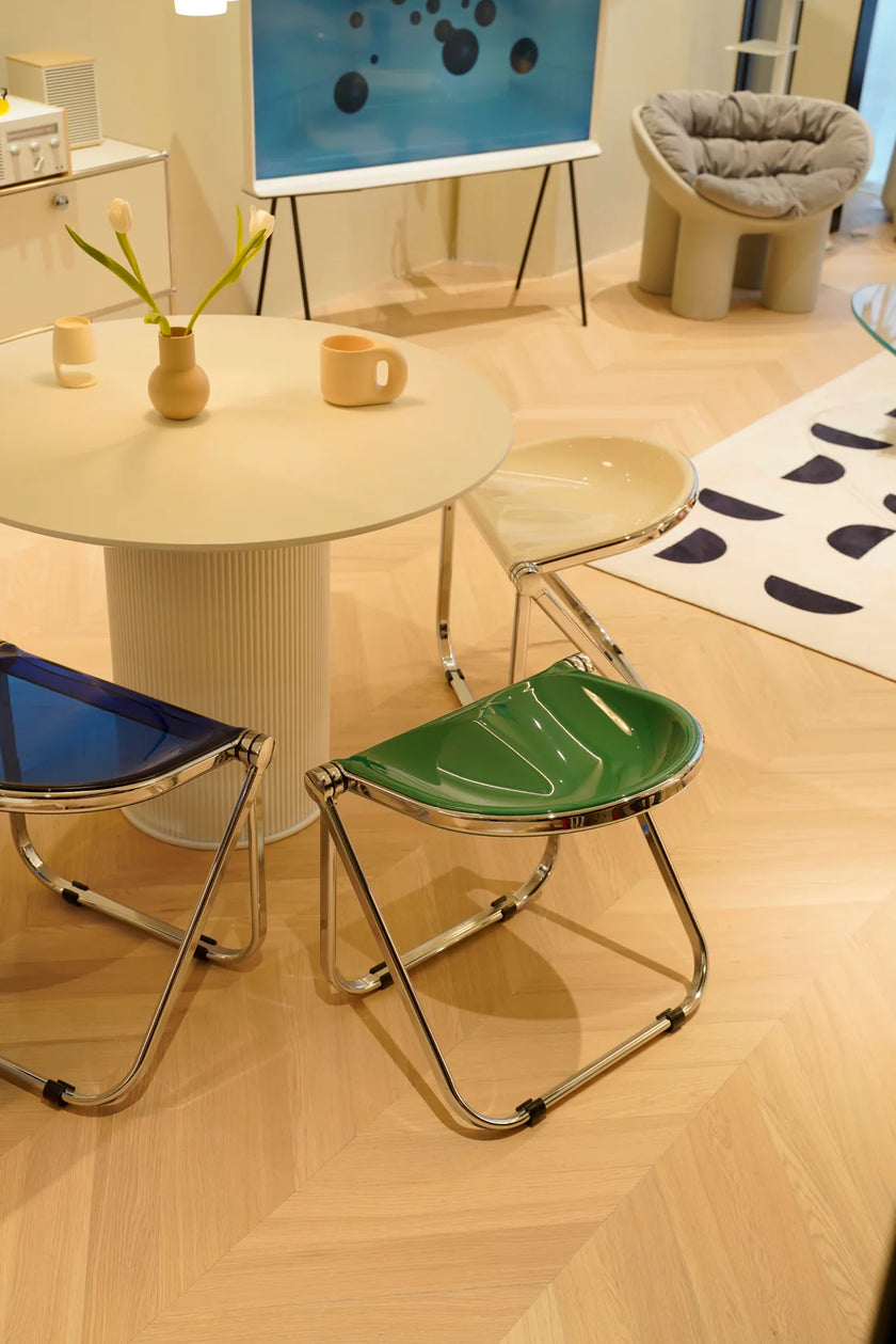 Modern room with a round table, three folding stools, and abstract art on the wall.