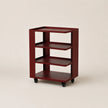 Wooden bookshelf with three shelves on wheels against a beige background