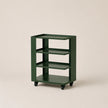 Green metal shelf with four shelves on wheels against a beige background