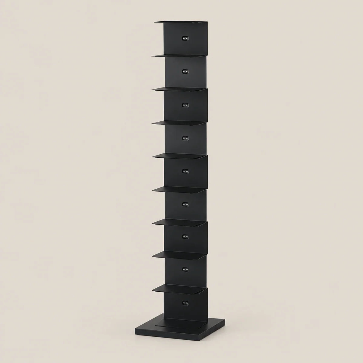 A tall, narrow black metal storage rack with multiple small shelves, shown against a plain warm beige background.
