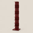 A tall, narrow red storage shelf with multiple compartments stacked vertically, set against a plain light beige background.