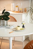 Small cake on a plate with a fork on a white round dining table, plant and candle in the background