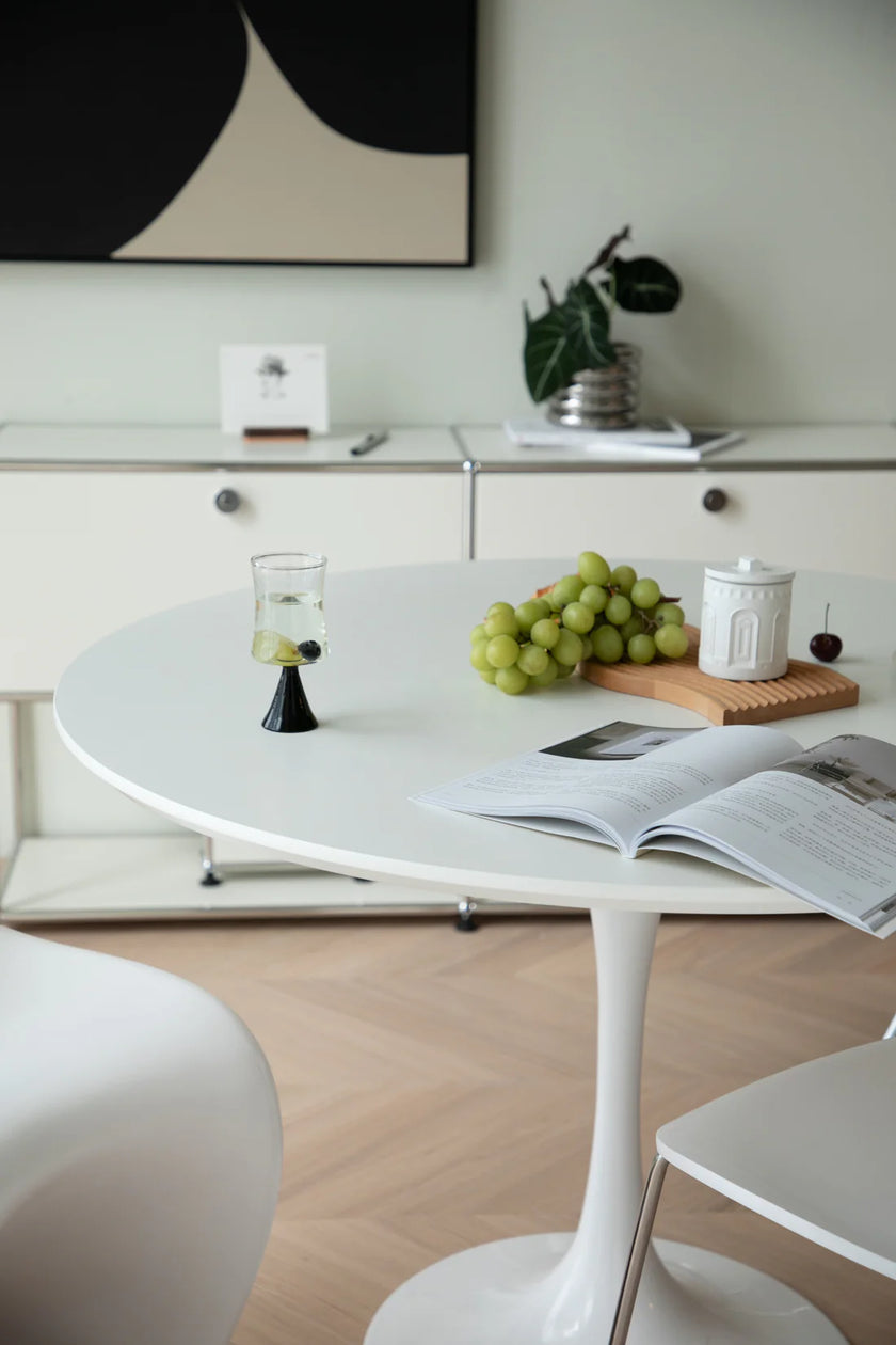 Modern kitchen with a round white dining table, chairs, and a magazine open on the table.