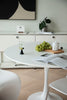 Modern kitchen with a round white dining table, chairs, and a magazine open on the table.