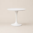White round table with a slender pedestal base on a beige background