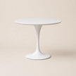 White round table with a pedestal base on a beige background