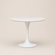 White round table with a pedestal base on a beige background