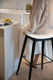 Women sitting on a black bar stool in a modern kitchen.