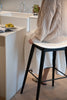 Women sitting on a black bar stool in a modern kitchen.
