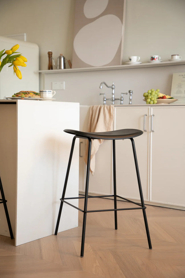 Bar stool in a kitchen setting with a white counter and cabinets.