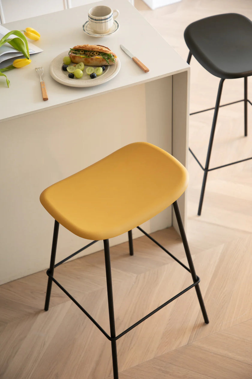 Yellow bar stool in a kitchen setting with a plate of food on a counter.