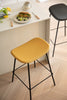 Yellow bar stool in a kitchen setting with a plate of food on a counter.