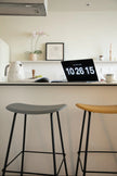 Two bar stools in a kitchen setting with a laptop displaying numbers on a white countertop.