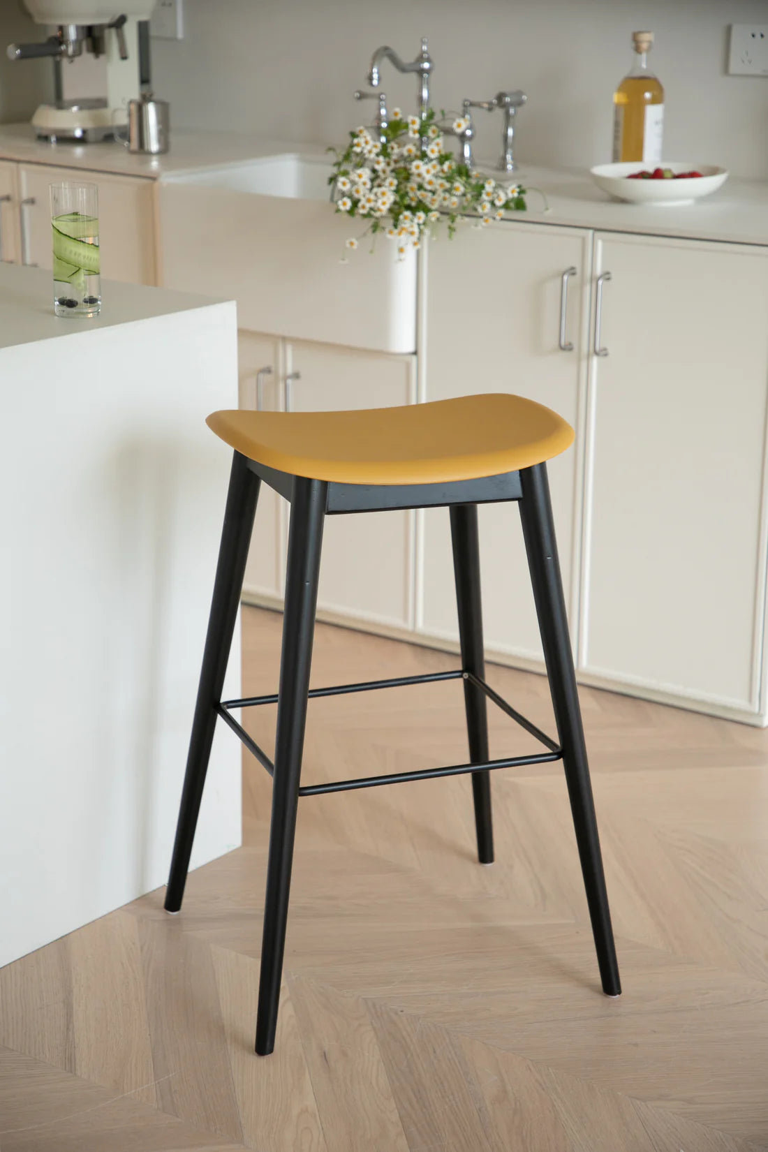 Yellow bar stool with black legs in a kitchen setting