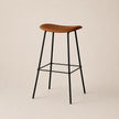 Bar stool with wooden seat and black metal legs on a beige background