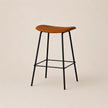 Bar stool with wooden seat and black metal legs on a beige background