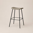 Bar stool with a gray seat and black metal legs on a beige background
