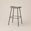 Bar stool with a green seat and black legs on a beige background