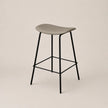 Bar stool with a gray seat and black metal legs on a beige background