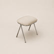 Stool with a cushioned seat and metal legs on a beige background