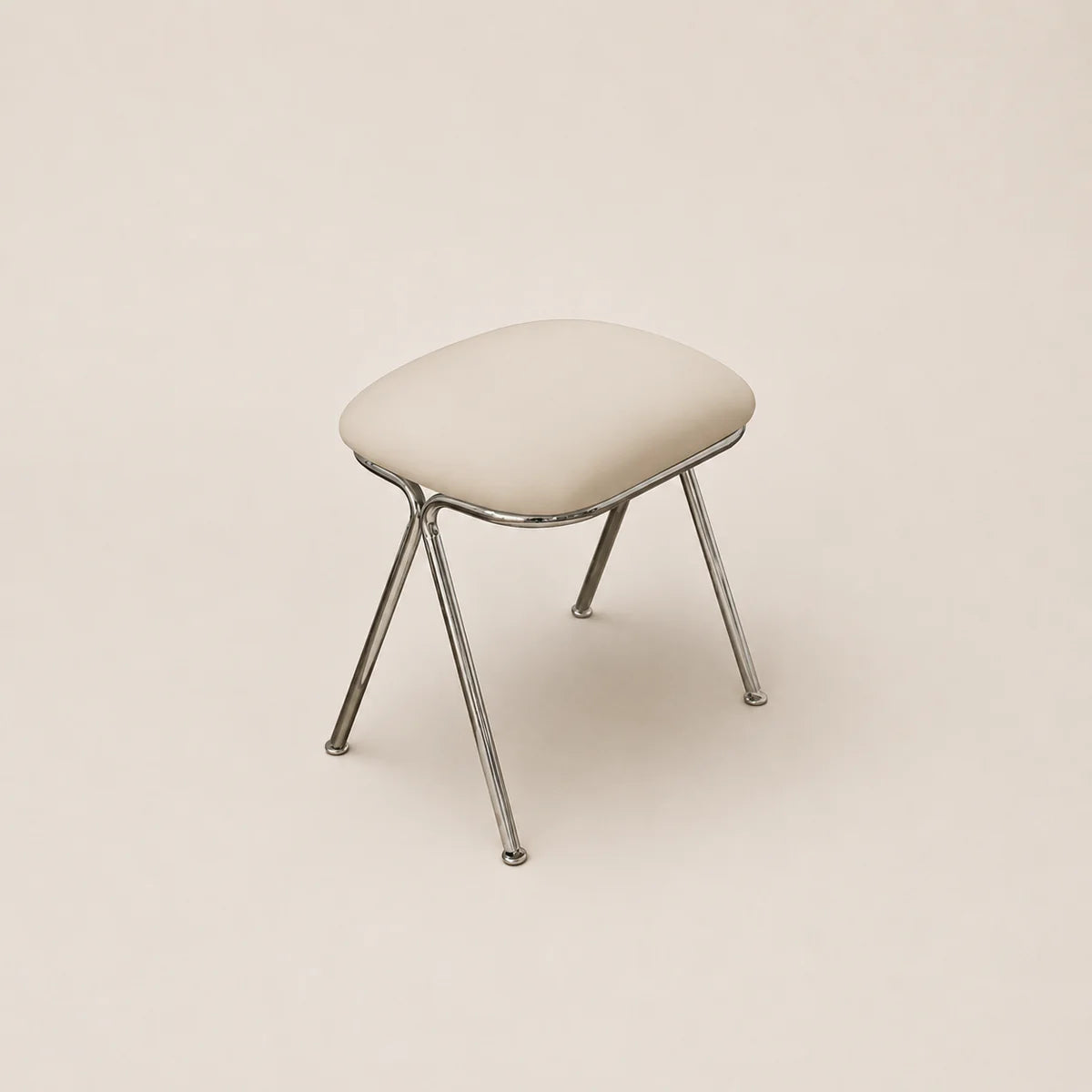 Stool with a cushioned seat and metal legs on a beige background