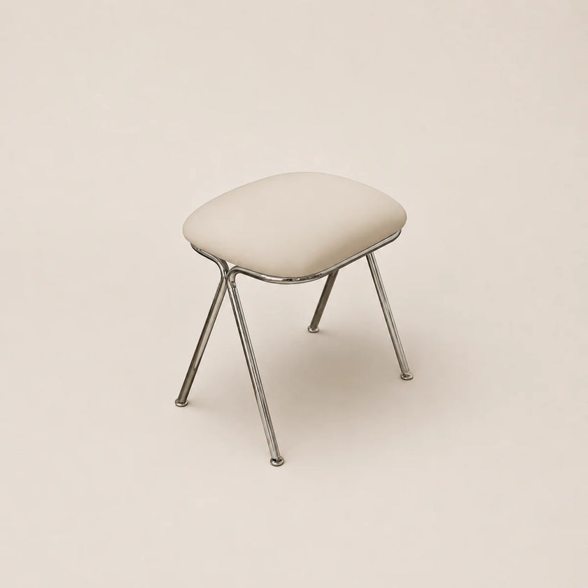 Stool with a cushioned seat and metal legs on a beige background