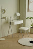 White vanity table with mirror and bathroom vanity stool in a room with a plant and lamp.