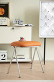 Orange vanity stool with metal legs in a room setting