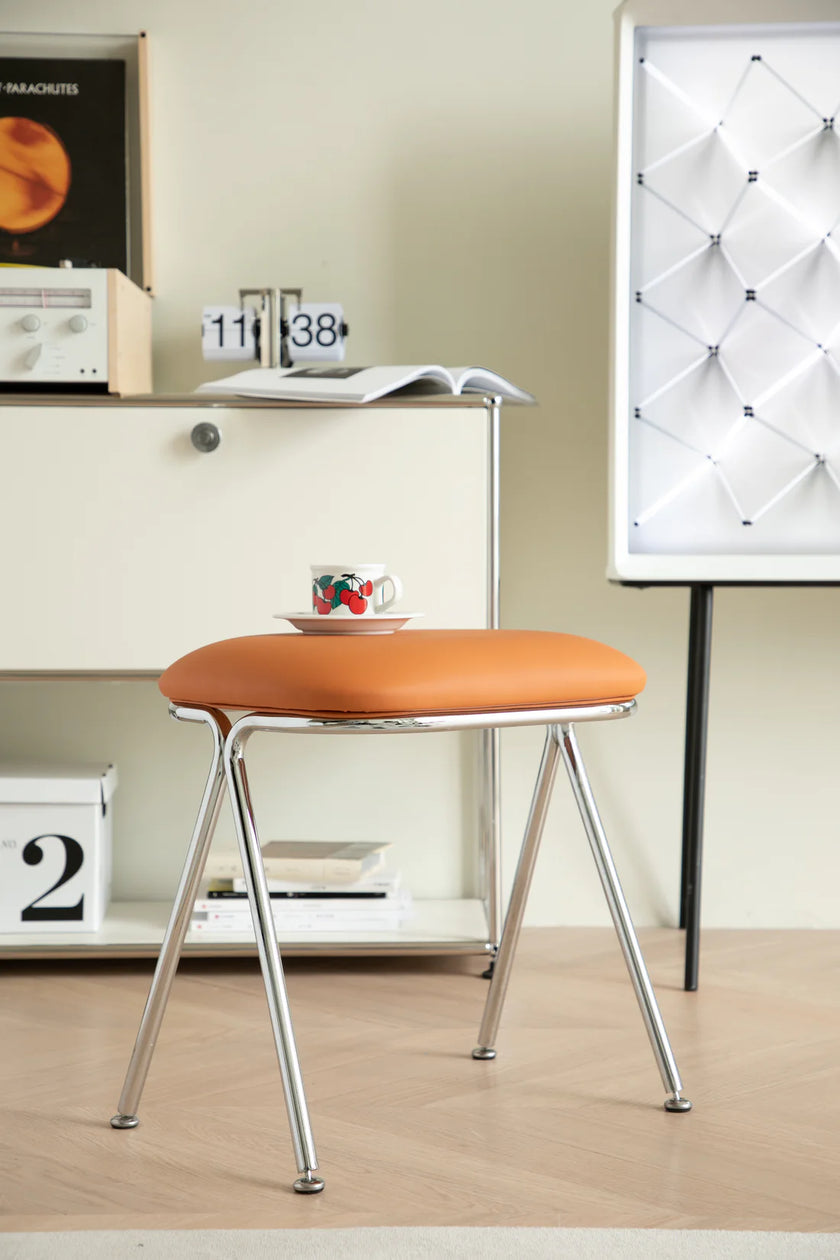 Orange vanity stool with metal legs in a room setting