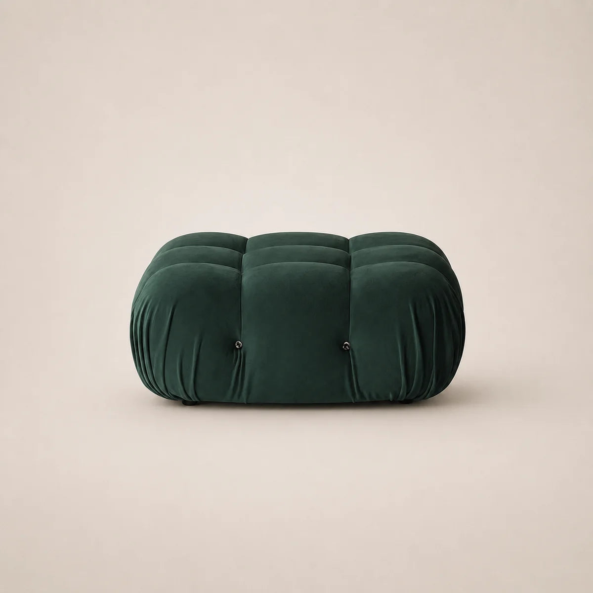 A forest green velvet tufted pouf or ottoman with a rounded rectangular shape, set against a solid light beige background.