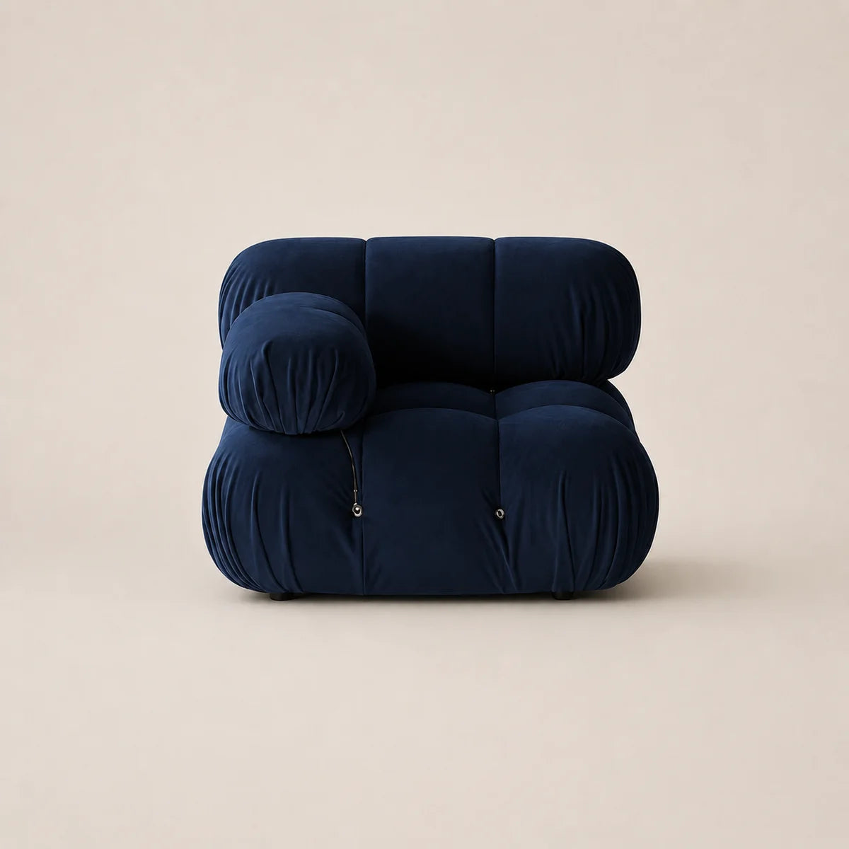 A modern modular floor cushion chair in deep steel blue velvet, featuring a rounded, cloud-like silhouette with zippered pockets, set against a solid warm beige background.