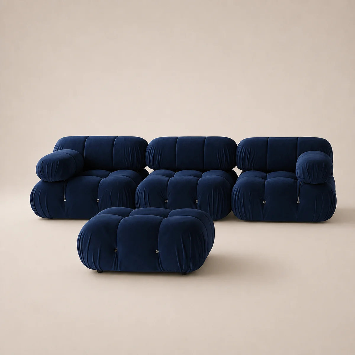 A modern modular sofa set in deep emerald steel blue velvet, featuring a low rectangular ottoman in front of a three-seater sofa and two matching armchairs, set against a warm beige studio background.
