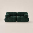 A pair of forest green modular upholstered armchairs with a rounded, cloud-like design and zippered front details, set against a solid light beige background.