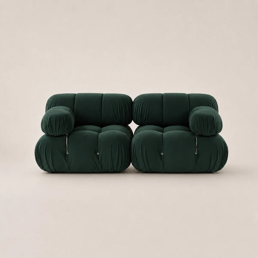 A pair of forest green modular upholstered armchairs with a rounded, cloud-like design and zippered front details, set against a solid light beige background.