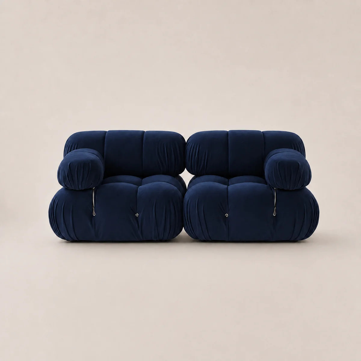A pair of modern, low-profile modular armchairs upholstered in deep steel blue velvet, set against a solid warm beige background.