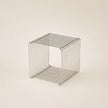 Wire mesh cube on a beige background