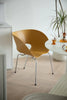 Modern yellow plastic chair in a minimalistic room with a white table and plant.