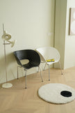 Modern interior with two plastic chair and a round rug on a wooden floor.