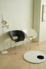 Modern interior with two plastic chair and a round rug on a wooden floor.