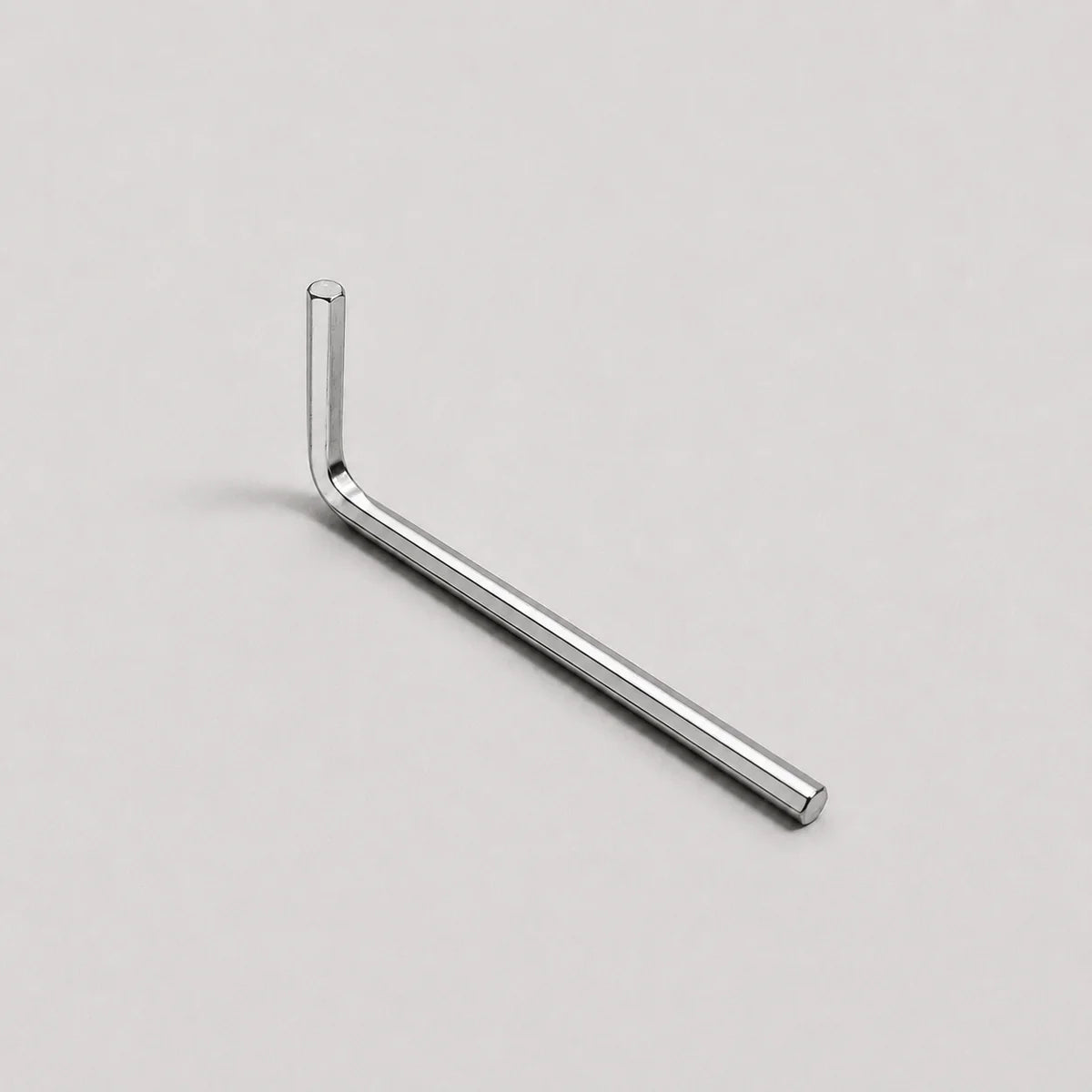 A silver metal hex wrench with an L-shaped head, shown diagonally on a light gray background.
