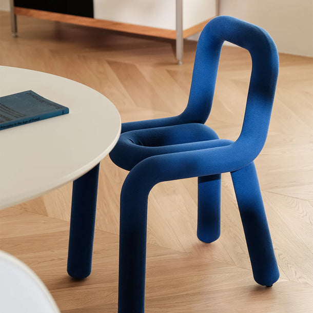 Blue chair on a wooden floor with a round table in the background