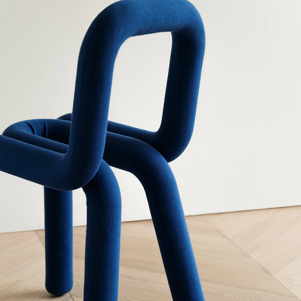 Blue chair with a modern design on a light wooden floor and white wall background