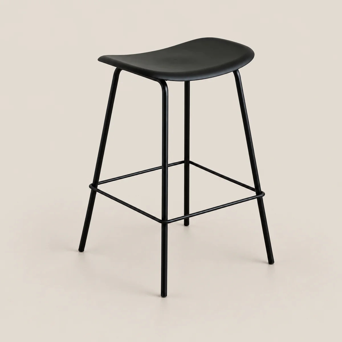 A modern black bar stool with a curved seat, slim metal legs, and a square footrest, shown against a solid light beige background.