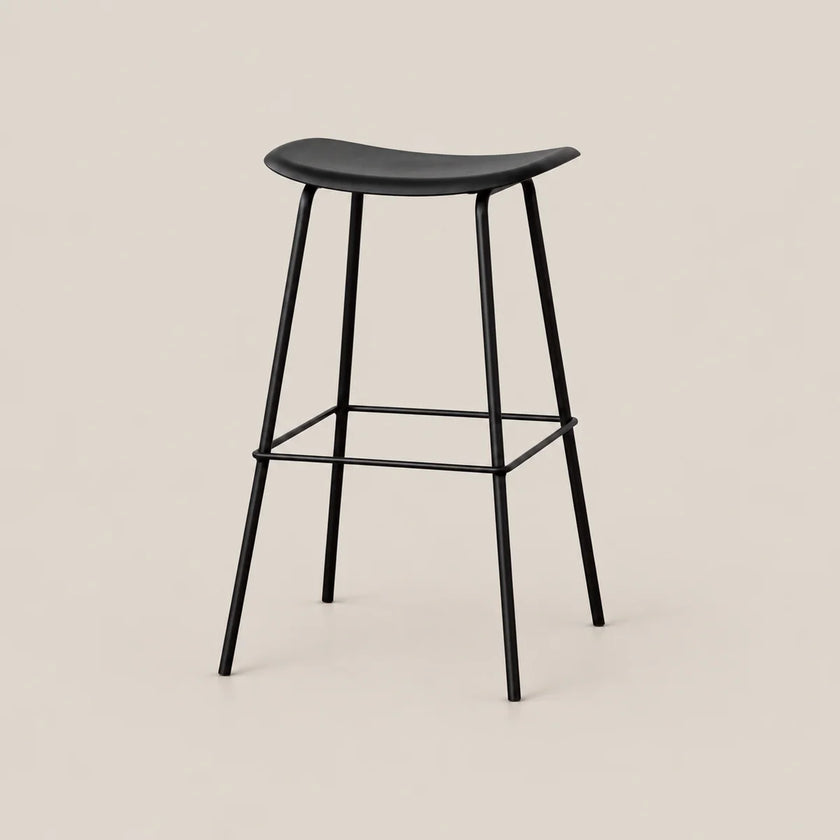 A modern black bar stool with a curved seat, slim metal legs, and a footrest, shown against a solid light beige background.