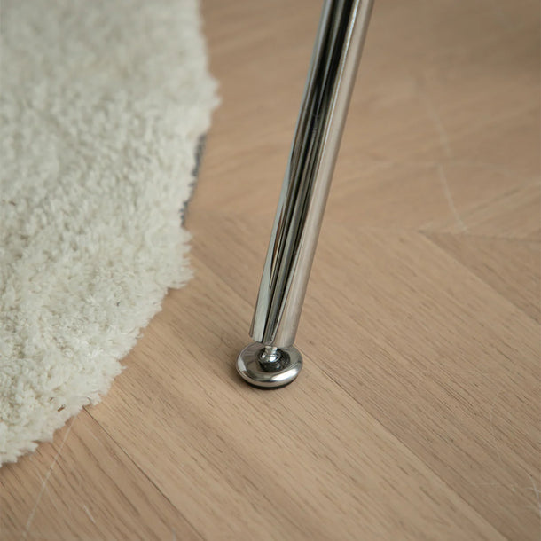 Metal leg of a piece of furniture on a wooden floor with a rug.