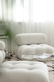 White upholstered chair and ottoman in a room with sheer curtains