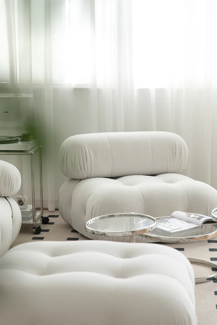 White upholstered chair and ottoman in a room with sheer curtains