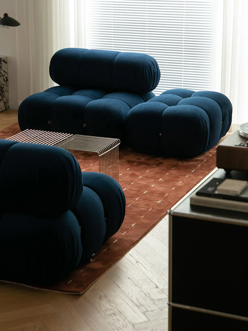 Modern living room with blue tufted chairs and a glass coffee table.