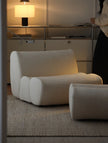 Modern beige armchair in a room with a lamp and reflective surface.